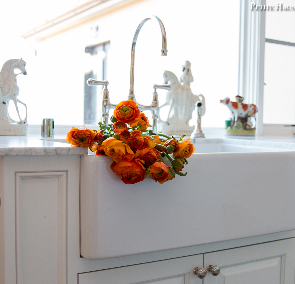 apron sink with white kitchen and bridge faucet